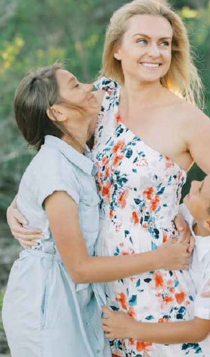 Ava Pyszczymuka laughing as Amelia and Luke hug her outdoors