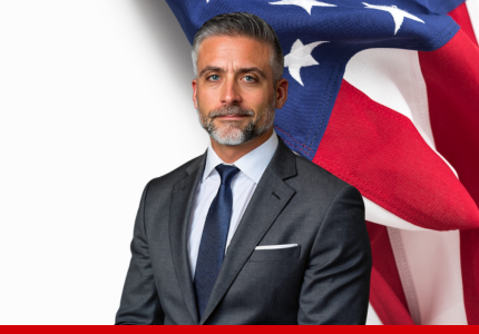 Campaign portrait of Martin Pyszczymuka in a dark suit standing in front of an American flag